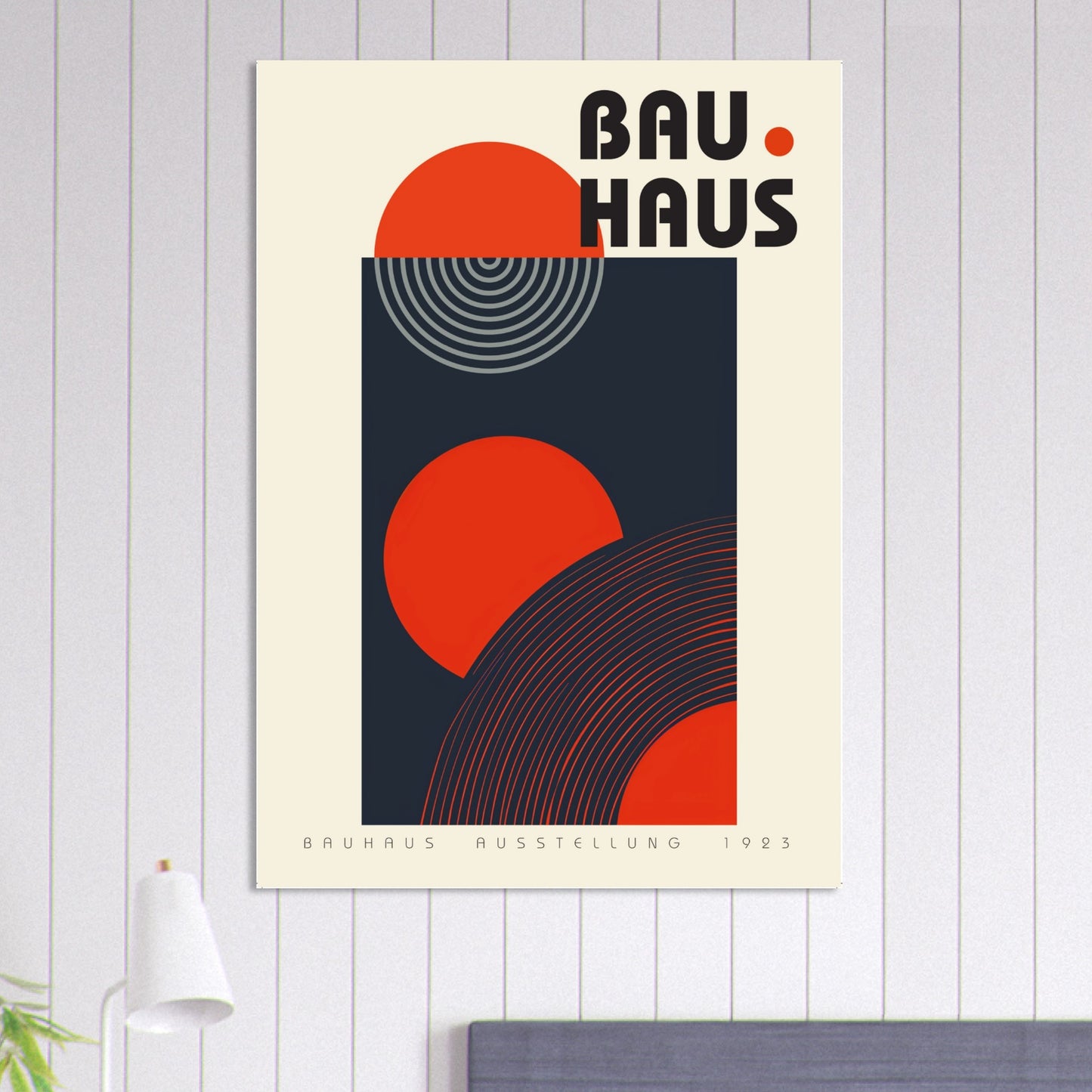 A framed Bauhaus Founders’ Print displayed on a green wall with indoor plants and warm lighting. The bold red and black geometric shapes contrast powerfully against the earthy background, adding a strong modernist presence and architectural rhythm to contemporary living spaces or creative studios.